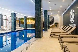 a swimming pool in a hotel lobby with lounge chairs at Continental SPA in Bukovel