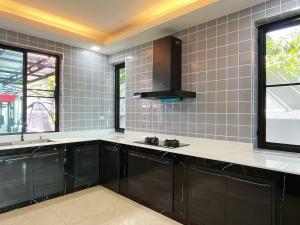 a large kitchen with black cabinets and a window at Live with lion in Chiang Mai