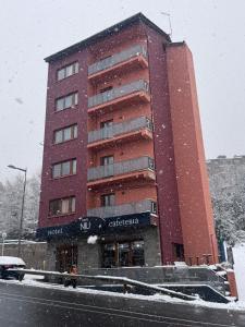 a tall red building with snow in front of it at Hotel NIU a 50 m del Funicamp in Encamp