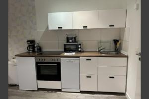 a kitchen with white cabinets and a stove and a sink at Günstige Ferienwohnung 2 Pers zentral Hamburg BoLA 48 in Hamburg