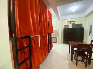 a dining room with orange curtains and a table at B2 Capsule Sleep Pods in Guiuan +16 photos