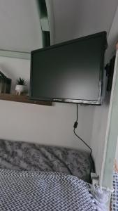 a flat screen tv hanging on a wall next to a bed at Blue bells Small but quirky & Cozy Shepherd's Hut in Halkyn