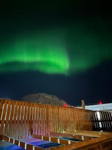 a fence with the aurora in the sky at Apartment Bjarmaland in Vestmannaeyjar