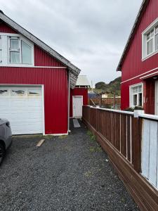 two red houses and a fence next to a car at Apartment Bjarmaland in Vestmannaeyjar +2 photos