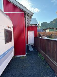 a red barn with a white door and a fence at Apartment Bjarmaland in Vestmannaeyjar
