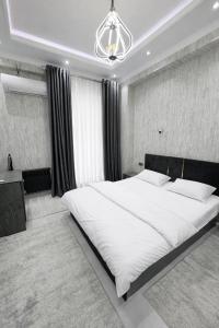 a bedroom with a large white bed and a chandelier at Boulevard 2BR Luxury Apartment in Tashkent