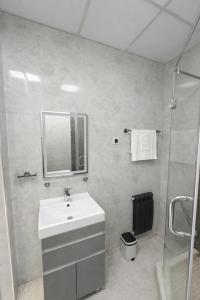 a white bathroom with a sink and a shower at Boulevard 2BR Luxury Apartment in Tashkent