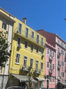 a yellow building with a balcony on a street at Daora Lisbon Beds in Lisbon