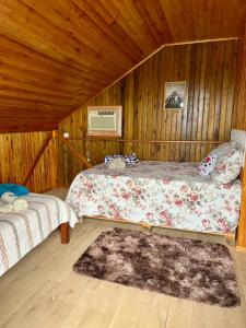 a bedroom with two beds in a wooden cabin at Pousada Canever in Lauro Müller