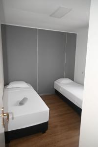 Zwei Betten in einem Zimmer mit weißen Wänden und Holzböden in der Unterkunft Hostel M in Maribor