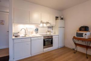 a kitchen with white cabinets and a sink and a refrigerator at Fully equipped holiday home for 6 in Nieuwpoort