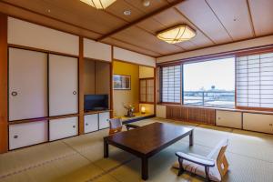 a living room with a table and chairs and a television at Biwako Grand Hotel Kyo-Ohmi in Otsu