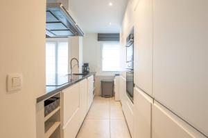 a kitchen with white cabinets and a tile floor at Amazing apartment for 8 with parking space in Ostend
