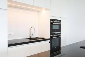 a kitchen with white cabinets and black appliances at Perfectly situated condo with amazing views in Ostend