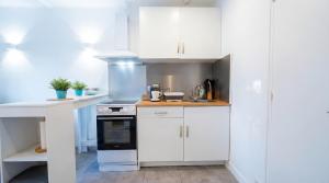 a white kitchen with white cabinets and a stove at Cozy & elegant, proche de Martigues in Saint-Mitre-les-Remparts +8 photos