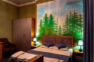a bedroom with a large painting of trees on the wall at Light Hostel by TripLE in Yakkasaray