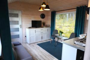 a living room with a tv and a kitchen with a window at Koziołkowo in Bartoszylas