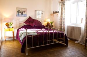a bedroom with a bed with purple sheets and a window at Le Jardin Secret in Monflanquin