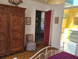 a bedroom with a bed and a large wooden cabinet at Le Jardin Secret in Monflanquin