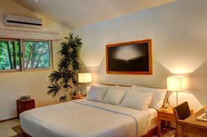 1 dormitorio con 1 cama y TV en la pared en Moana Surf Resort, en Nosara