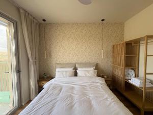 a bedroom with a white bed and a window at בקצה הוואדי - The Wadi Edge in Yeroẖam