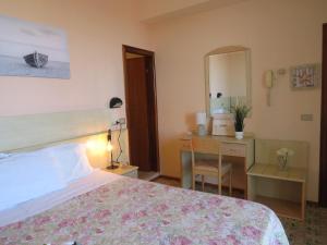 a bedroom with a bed and a desk and a mirror at Hotel Primula in Cesenatico
