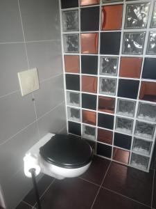 a bathroom with a black toilet and a wall of tiles at L'Instant des Hôtes in Combrit +22 photos