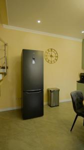 a black refrigerator in a room with a clock on the wall at Esal Manas in Jalal-Abad +2 photos