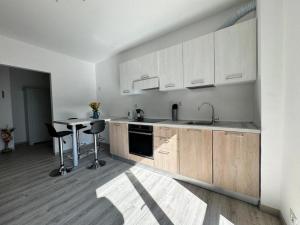 a kitchen with white cabinets and a table with chairs at Apartment NicoCeli in Châtillon