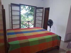 a colorful bed in a room with a window at Ecovila in São Sebastião