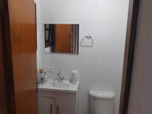 a bathroom with a sink and a toilet and a mirror at Ecovila in São Sebastião