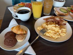 a table topped with plates of breakfast foods and coffee at Hotel Bishops Arms Kristianstad in Kristianstad