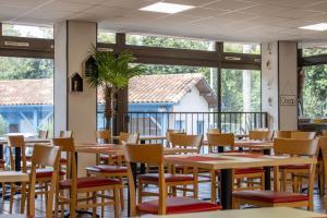 a dining room with tables and chairs and windows at Camping les Criques de Royan in Saint-Georges-de-Didonne