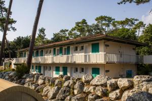 a building with green doors and a stone wall at Camping les Criques de Royan in Saint-Georges-de-Didonne