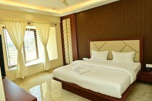 a bedroom with a large bed with white sheets at Siddarth Residency in Channarāyapatna