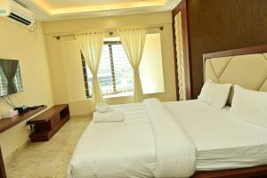 a bedroom with a large white bed and a window at Siddarth Residency in Channarāyapatna