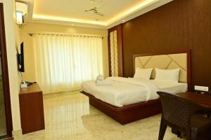 a hotel room with a bed and a desk and a television at Siddarth Residency in Channarāyapatna +7 photos