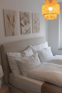 a bed with white pillows and pictures on the wall at Horizon 62 I Zürich Lakeside Apartment I Modern I Free Parking I Self-Check-In in Richterswil