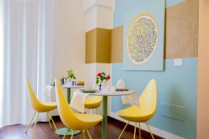 a dining room with a table and yellow chairs at Rose Iconic Rooms in Lecce
