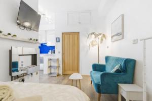 a living room with a blue chair and a television at Shiny Pebble in Southwold
