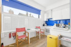 a kitchen with white cabinets and a table and chairs at Shiny Pebble in Southwold