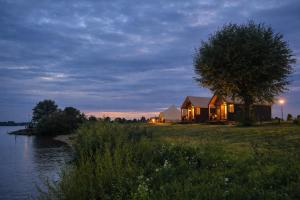 a house on the shore of a river at night at Luxury Suite in Heerewaarden