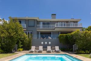 a villa with a swimming pool and a house at Plett Azure Guesthouse in Plettenberg Bay