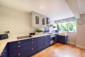 a large kitchen with blue cabinets and a large window at 3 Bed in Belper oc-dcbobb in Belper +9 photos