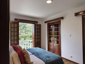 a bedroom with a bed and a large window at Casa do Vale in São Vicente