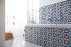y baño con bañera y azulejos azules y blancos. en Hostal La Casa Sanlúcar, en Sanlúcar de Barrameda