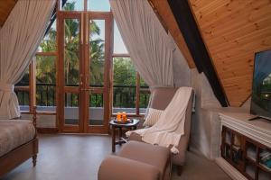 a living room with chairs and a tv and windows at Anjuna Casa Nova in Jāmb