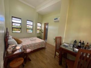 a bedroom with a bed and a desk and two windows at B2-B Guesthouse in Guiuan