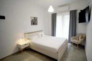 a bedroom with a white bed and a chair at AsproLux Seaside Studios in Asprovalta