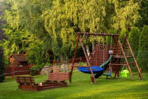 a playground with two benches and a swing at Domek z bali in Jarnołtówek
